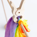 Rainbow cotton cloth from Trigonos big start held by a giant wooden peg on wooden frame pole