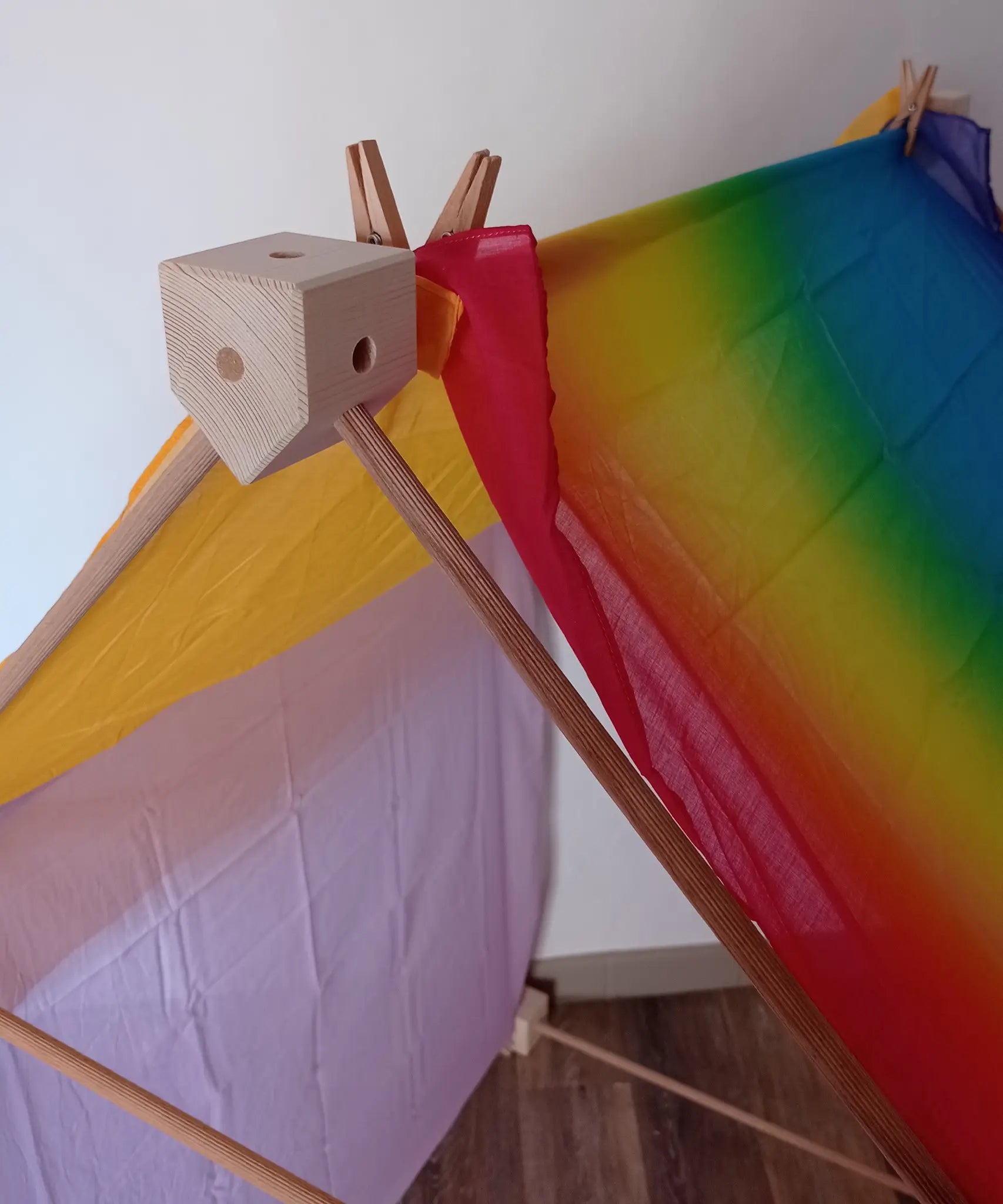 Wooden corner piece holding the tent roof made from the Trigonos big start set with a rainbow cloth on top