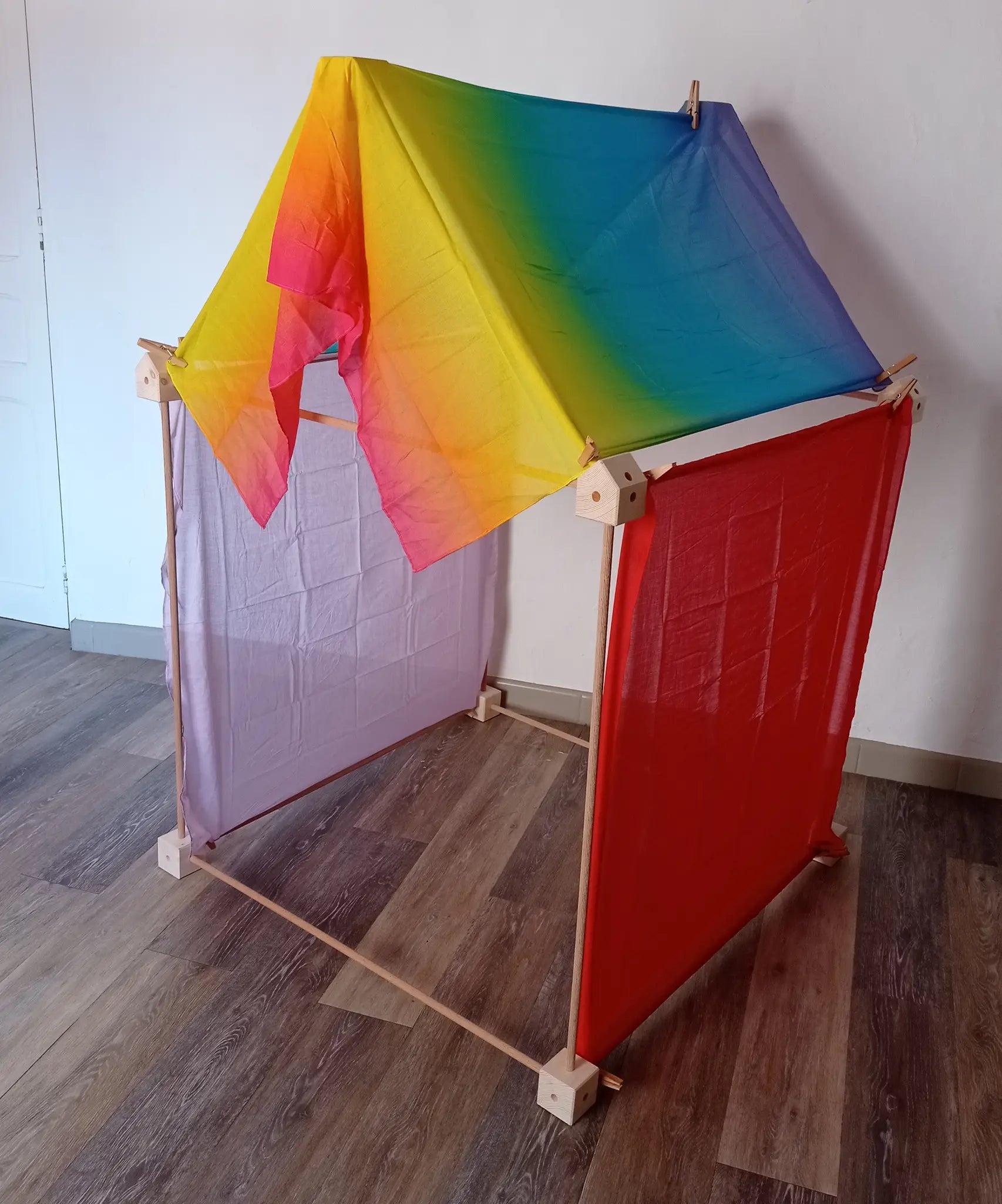 Simple tent build made from the wooden Trigonos big start set showing a rainbow cloth on the roof and coloured cloths on the side