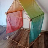 Trigonos big start set showing a tent made up from wooden poles and corner blocks with a rainbow cloth laid on top of the frame