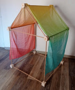 Trigonos big start set showing a tent made up from wooden poles and corner blocks with a rainbow cloth laid on top of the frame