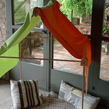 A tent setup made from the Trigonos wooden big start set showing a rainbow cloth on top of the frame and cushions inside