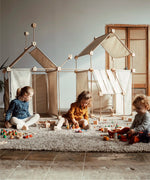 Multiple dens built from the Trigonos family wooden construction set with children playing with wooden toys 