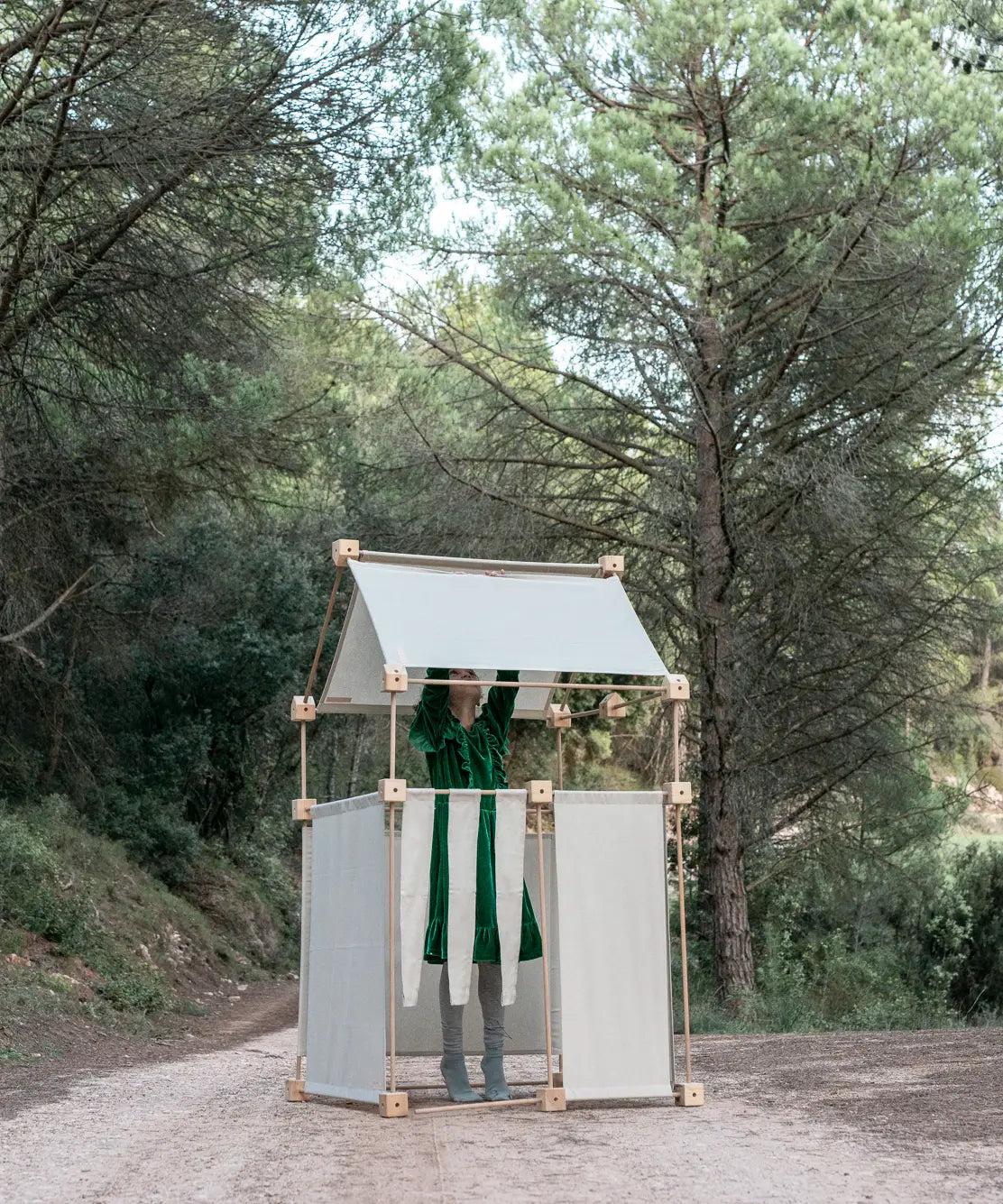 Child inside a den made from the Trigonos family wooden  construction set in a forestry