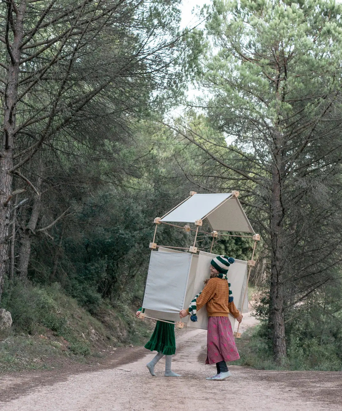 A den made from the Trigonos wooden construction set carried by 2 children in a forestry 