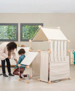 Mother and child standing next to a tent made from the Trigonos family organic wooden construction set 