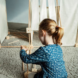 Child building using wooden poles and blocks from the Trigonos kernel organic family construction set