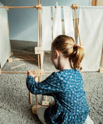 Child building using wooden poles and blocks from the Trigonos kernel organic family construction set