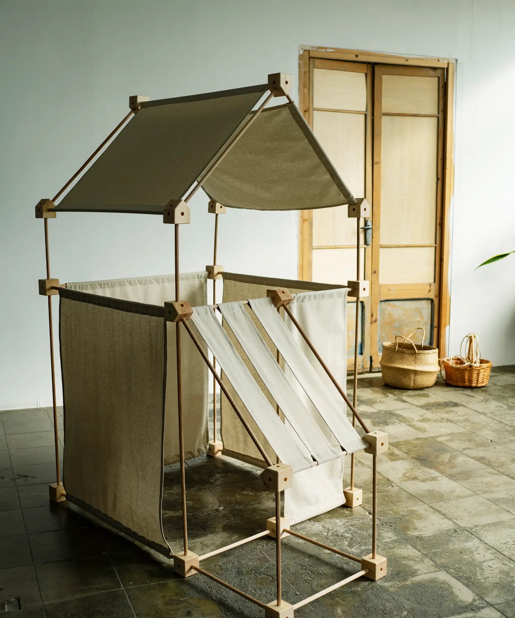 A tent structure made from the Trigonos kernel organic family wooden construction set standing on a concrete surface