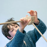 Child placing wooden poles into a corner block for the roof used from the Trigonos kernel organic set