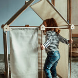 Child playing inside a Trigonos wooden kernel organic construction set in a living room setting