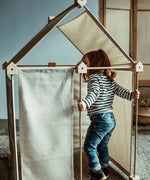 Child playing inside a Trigonos wooden kernel organic construction set in a living room setting