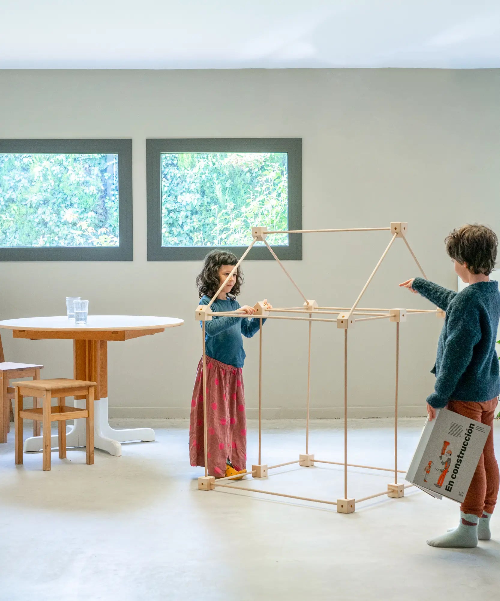 Children building a a tent structure using the Trigonos wooden kernel organic construction set in a dining room setting