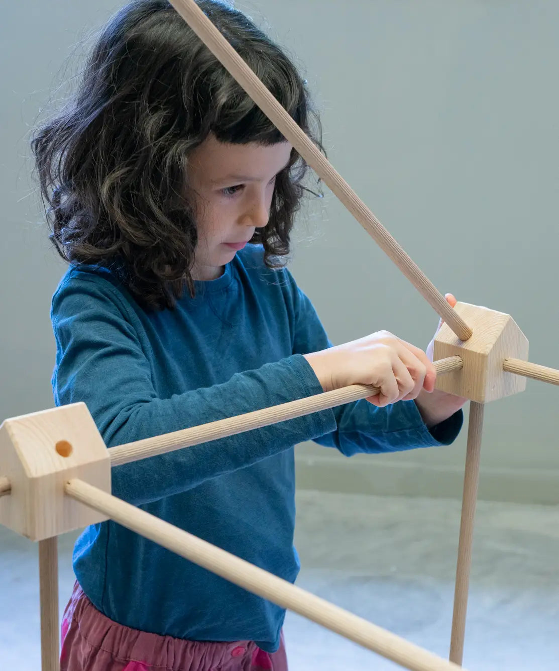 Child placing wooden poles into a corner block used from the Trigonos kernel organic set