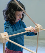Child placing wooden poles into a corner block used from the Trigonos kernel organic set