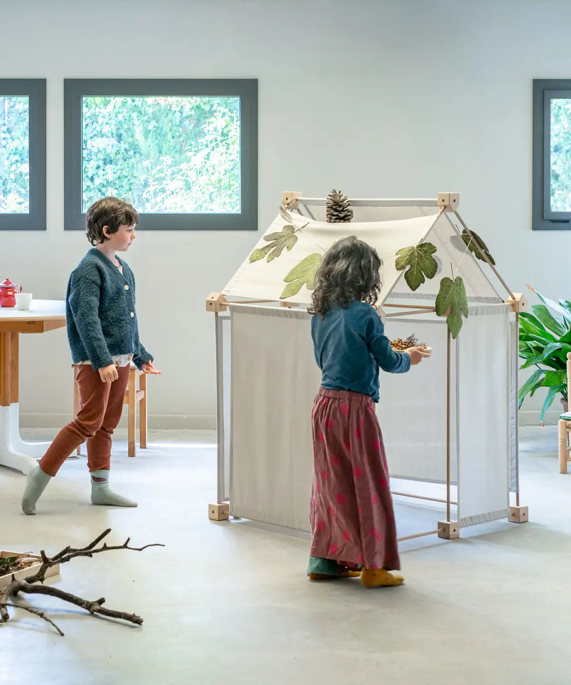 Children placing leaves on the roof of a build using the Trigonos kernel organic set showing white cotton sheets on the sides 