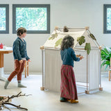 Children placing leaves on the roof of a build using the Trigonos kernel organic set showing white cotton sheets on the sides 