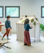 Children placing leaves on the roof of a build using the Trigonos kernel organic set showing white cotton sheets on the sides 