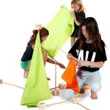 Children assembling wooden poles into blocks and coloured cotton sheets from the Trigonos maxi green construction set.