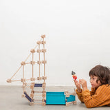 A pirate ship made from the Trigonos wooden medium construction kit standing next to a child on a concrete floor