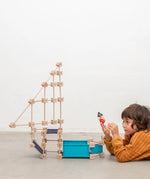 A pirate ship made from the Trigonos wooden medium construction kit standing next to a child on a concrete floor