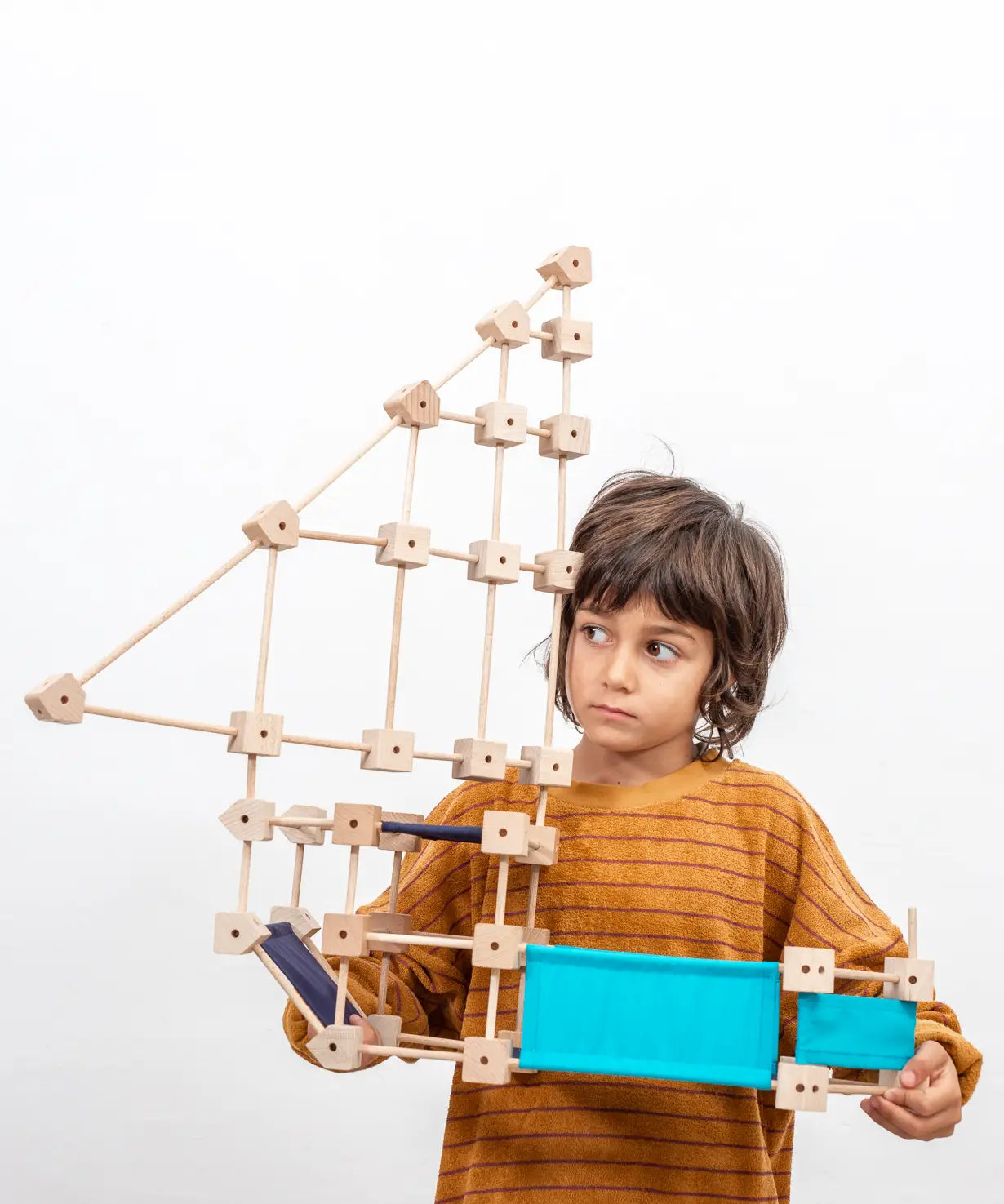 Child holding a pirate ship made from the Trigonos medium construction kit showing dark and blue cotton sheets 