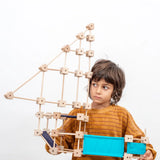 Child holding a pirate ship made from the Trigonos medium construction kit showing dark and blue cotton sheets 