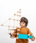 Child holding a pirate ship made from the Trigonos medium construction kit showing dark and blue cotton sheets 