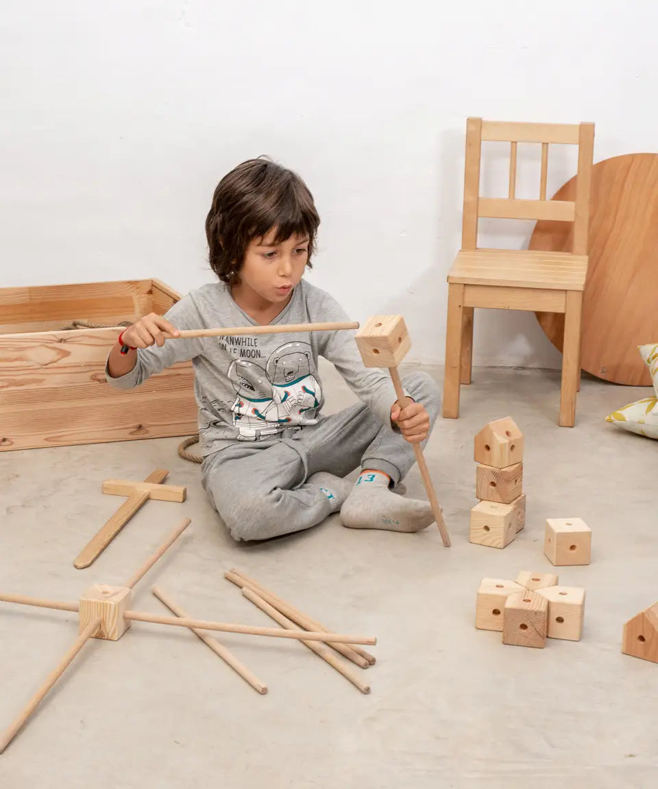 Child using the poles and corner block pieces from the Trigonos wooden starter set to build a structure