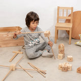 Child using the poles and corner block pieces from the Trigonos wooden starter set to build a structure