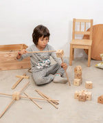Child using the poles and corner block pieces from the Trigonos wooden starter set to build a structure