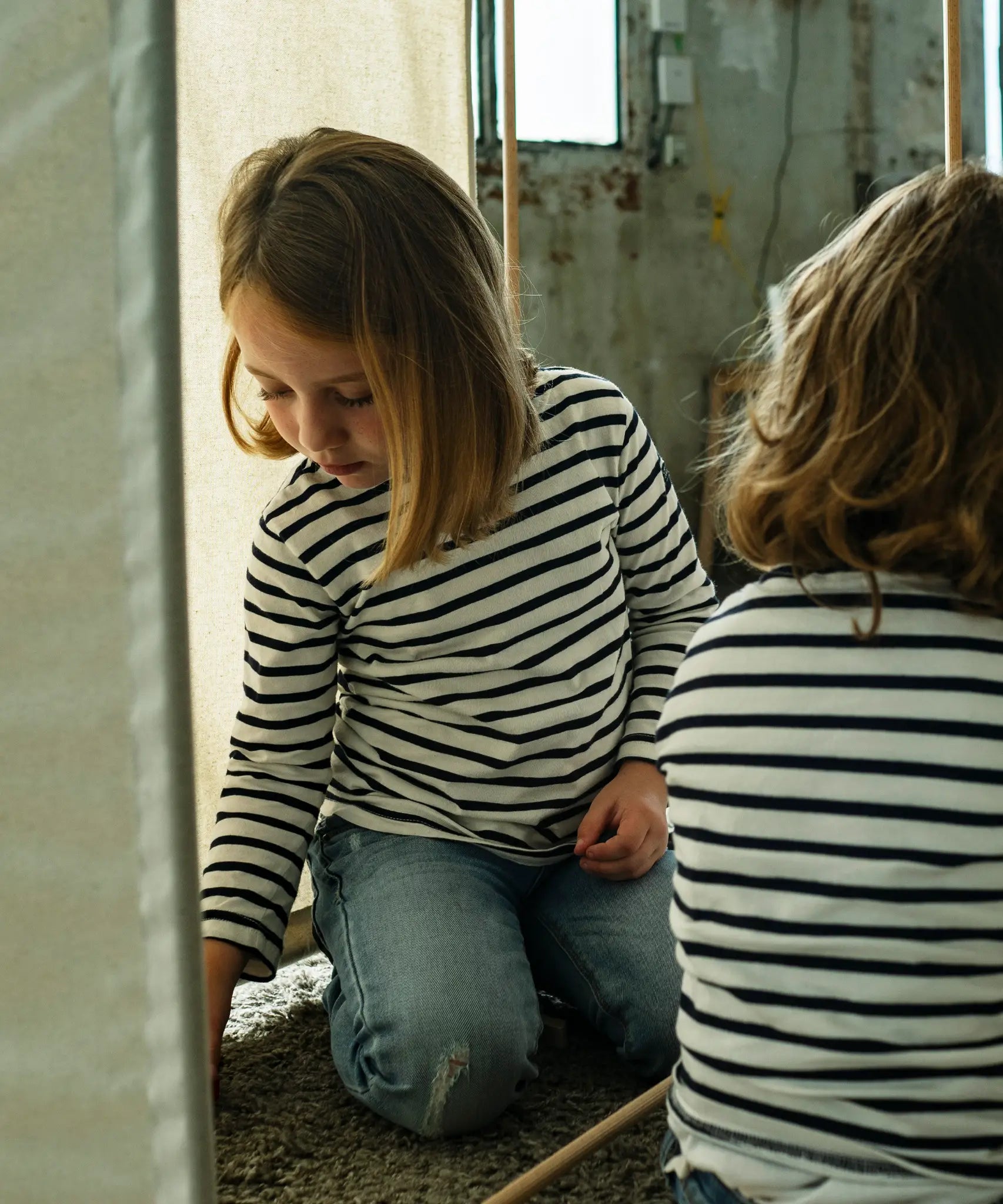 Child playing inside a tent structure made from the Trigonos wooden kernel organic construction set