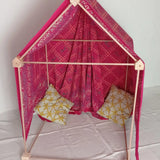 A cosy tent setup made from the Trigonos wooden big start set showing a decorated pink cloth on top of the frame and cushions inside