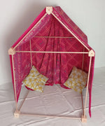 A cosy tent setup made from the Trigonos wooden big start set showing a decorated pink cloth on top of the frame and cushions inside