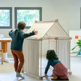 Children building a tent using the Trigonos kernel organic set showing white cotton sheets on the sides and roof
