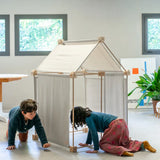 Children playing inside a tent made from the Trigonos wooden kernel organic construction set on a concrete surface
