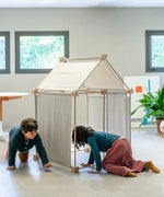 Children playing inside a tent made from the Trigonos wooden kernel organic construction set on a concrete surface
