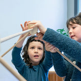 Children placing wooden poles into a corner block for the roof used from the Trigonos kernel organic set