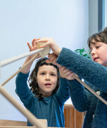Children placing wooden poles into a corner block for the roof used from the Trigonos kernel organic set