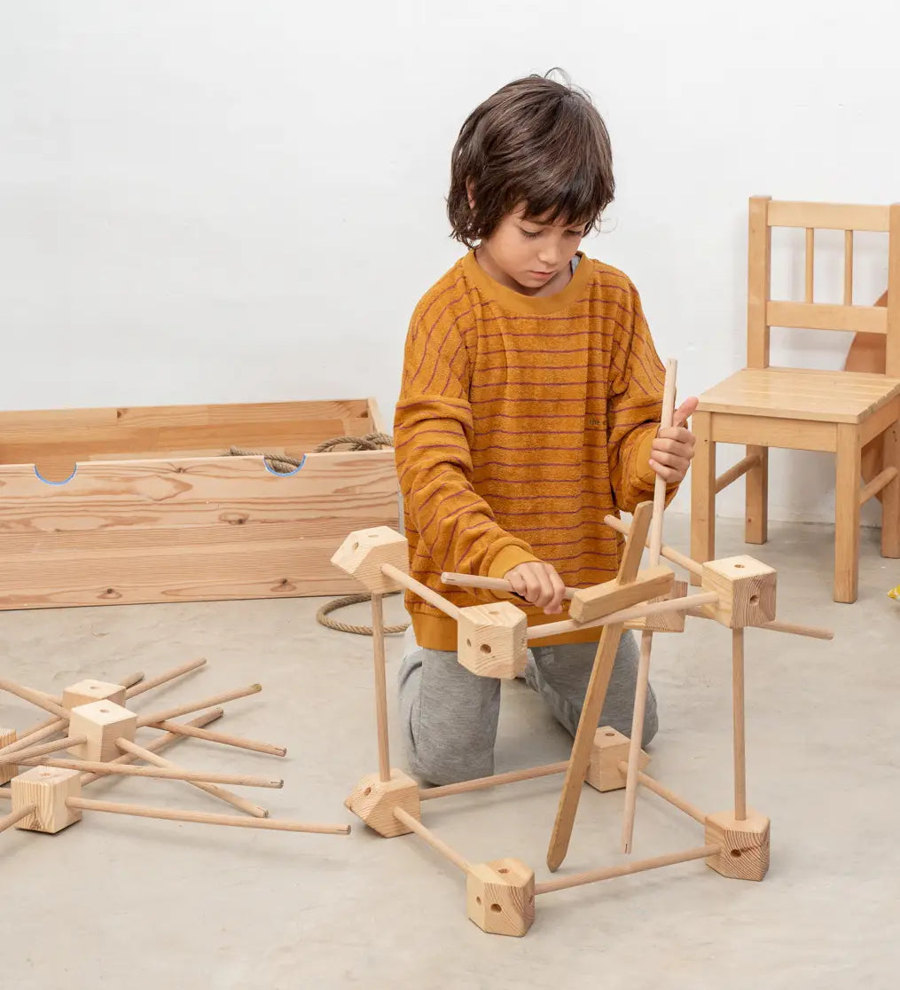 Child building a structure using pieces from the Trigonos wooden starter set
