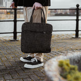 A woman standing next to a city canal, holding the Turtle Bags zig zag duffle bag