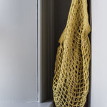 Turtle Bags organic long handle shopping bag hanging from a white wall