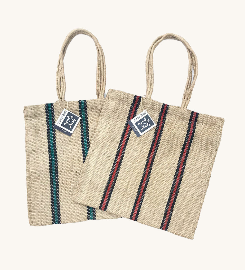 Two Turtle Bags hand woven jute tote bags with long handles, one in a green and black stripe design and one with red and black stripes