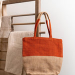 Turtle Bags eco-friendly orange block colour tote bag hanging on a wooden hook in front of a white wall