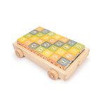 Uncle Goose wooden alphabet blocks lined up in the Uncle Goose pull wagon on a white background