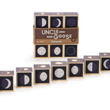 Uncle Goose handmade wooden moon cubes lined up in order of phases on a white background in front of their packaging
