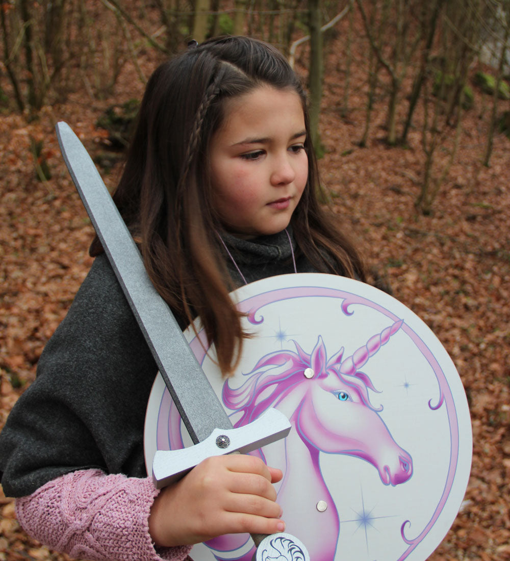 Child pictured with the Vah Arabella Unicorn Wooden Sword in one hand and the matching arabella shield in the other hand