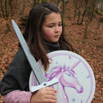 Child pictured with the Vah Arabella Unicorn Wooden Sword in one hand and the matching arabella shield in the other hand