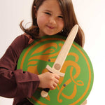 child smiling holding a Celtic sigar shield and a wooden wiki dagger
