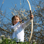 A child holding up the Vah Junior Wooden Bow with a blue Safety Arrow in placed ready to be fired. 